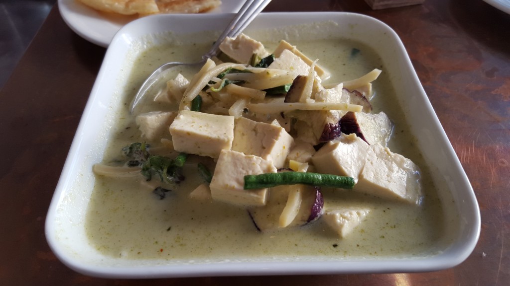 Green curry with roti lurking in the background.